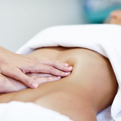 Hands massaging female abdomen.Therapist applying pressure on be Hands massaging female abdomen.Therapist applying pressure on belly. Woman receiving massage at spa salon